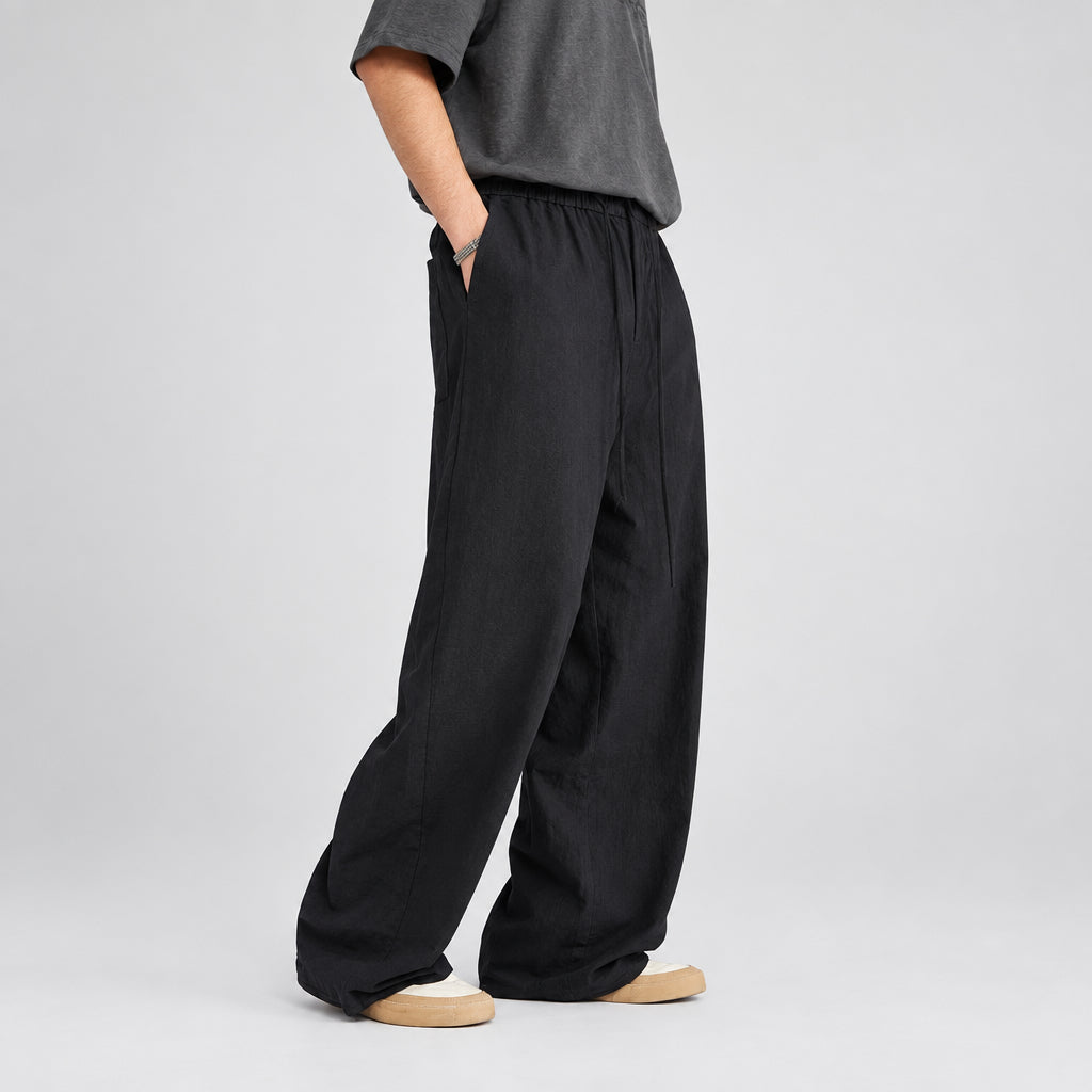 Black linen-blend wide-leg trousers with elastic waist, side pockets, and relaxed drape