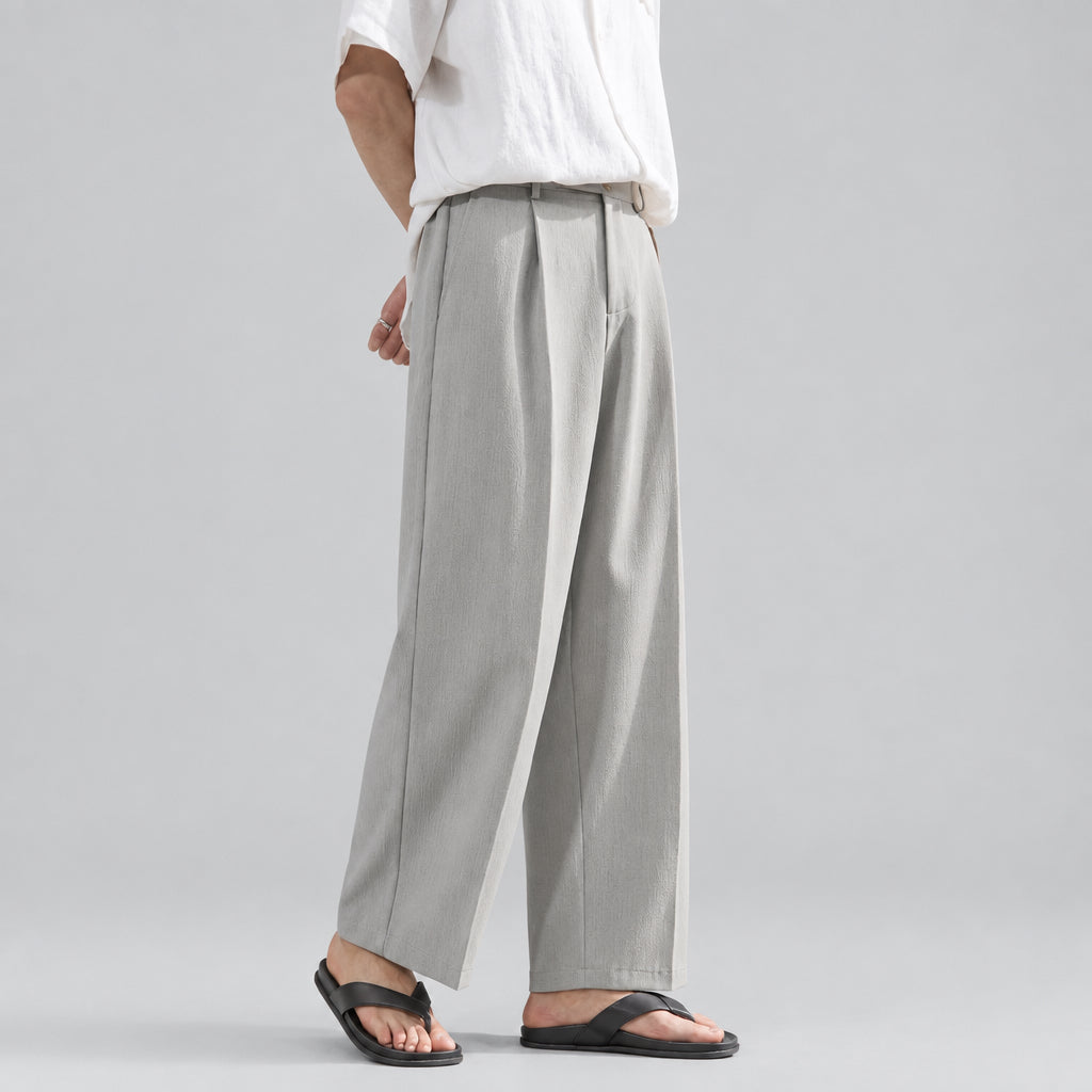 Pleated drape trousers in gray, wide-leg silhouette with front crease and belt loops.
