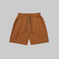 Rust-orange technical training shorts with elastic waistband, drawstring, and side pockets.