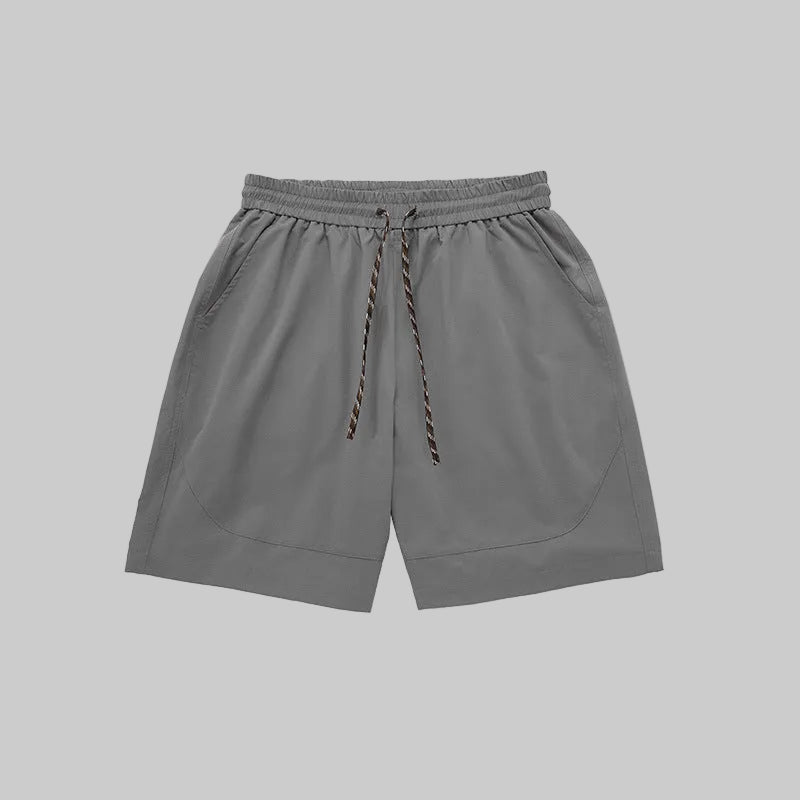 Gray technical training shorts with elastic waistband, drawstring, and side pockets.