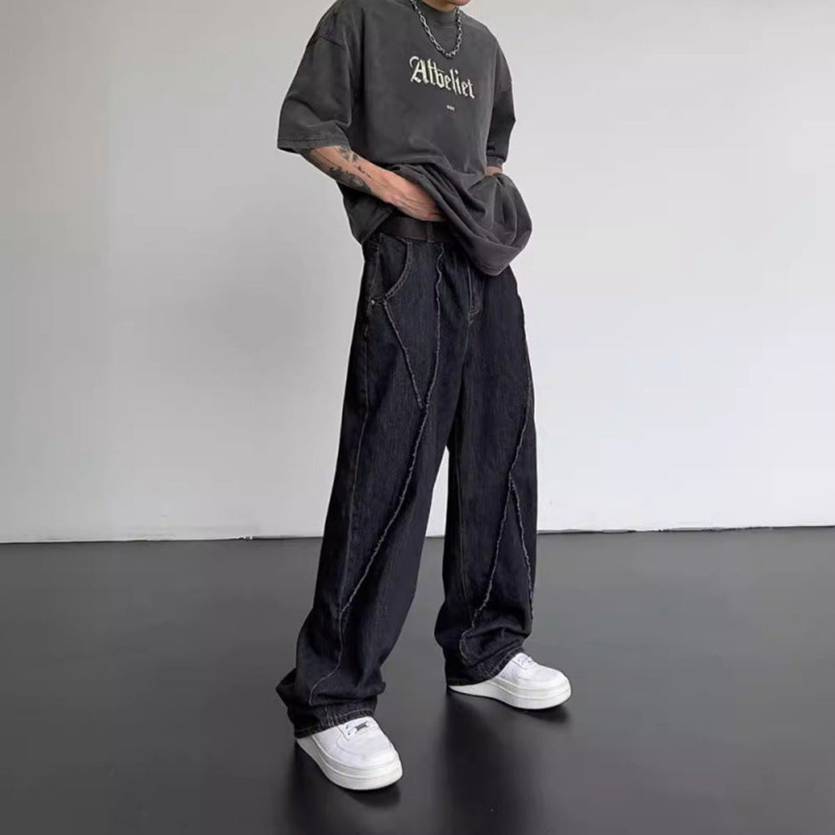 Black straight-leg jeans with relaxed fit, button waist, and long diagonal panel seams