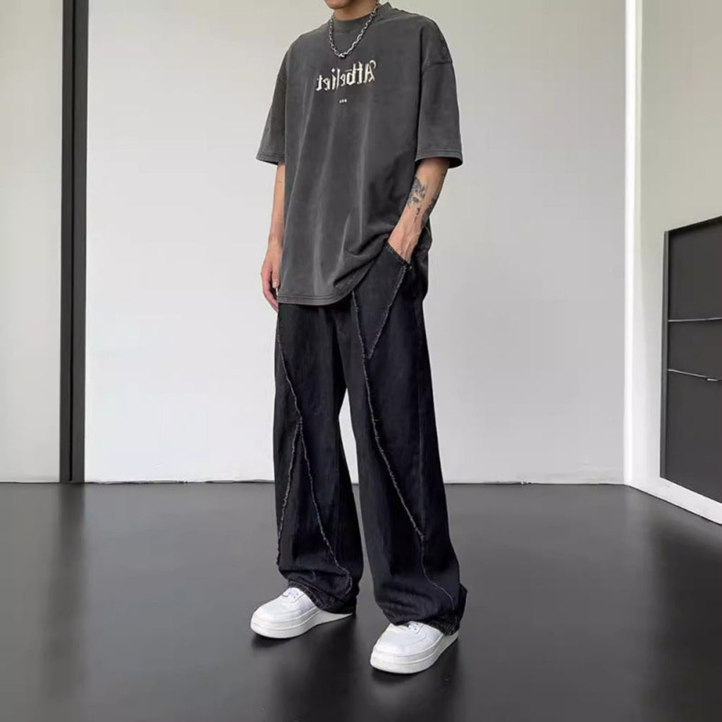 Black straight-leg jeans with wide legs, front fly, and stitched diagonal panel detailing