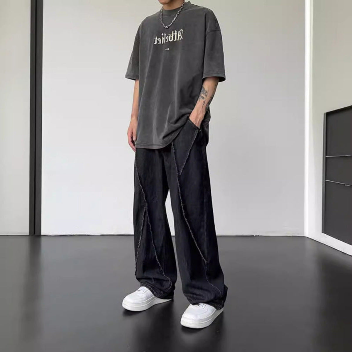 Black straight-leg jeans with wide legs, front fly, and stitched diagonal panel detailing