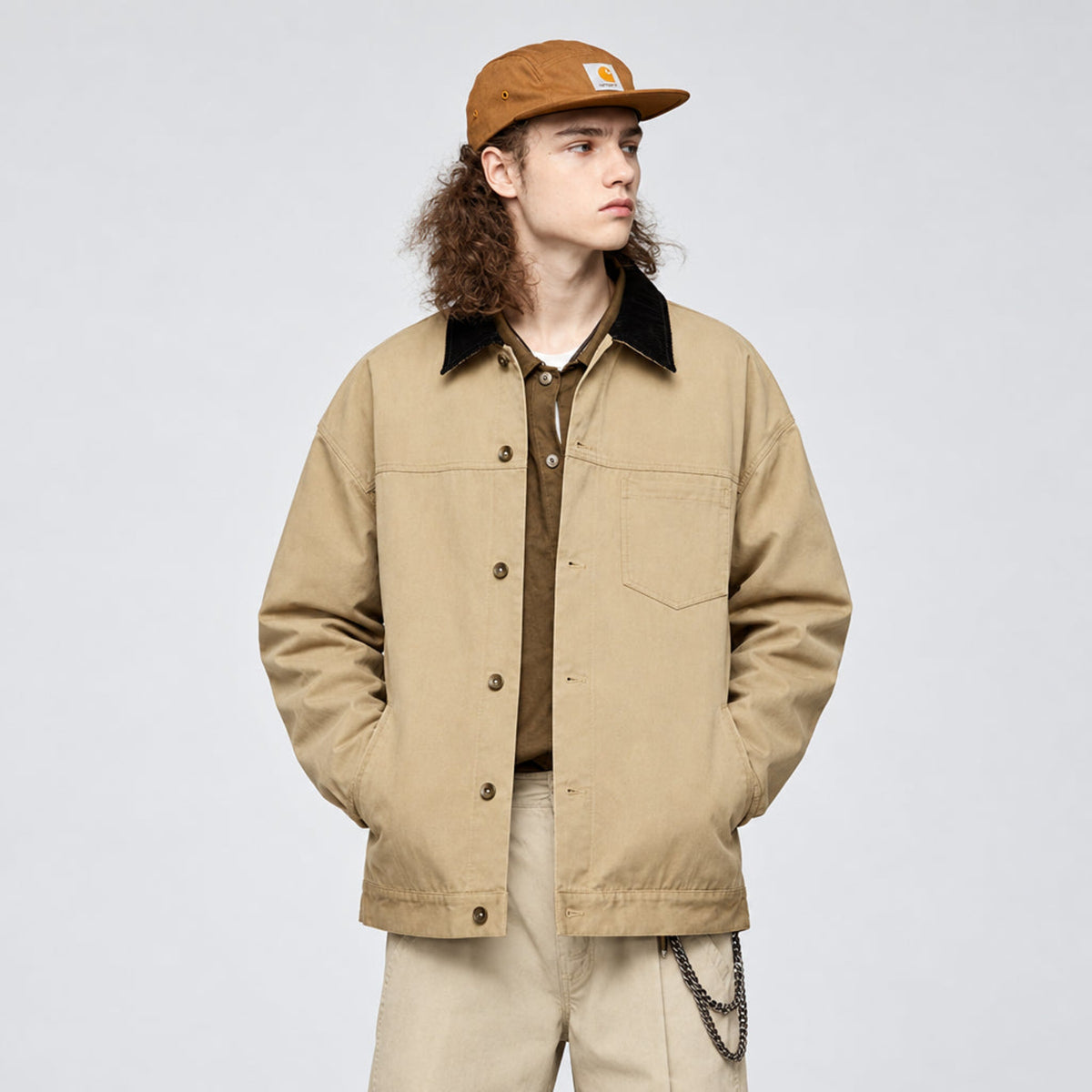 Khaki button-up jacket with black collar and chest pocket, worn by model with cap