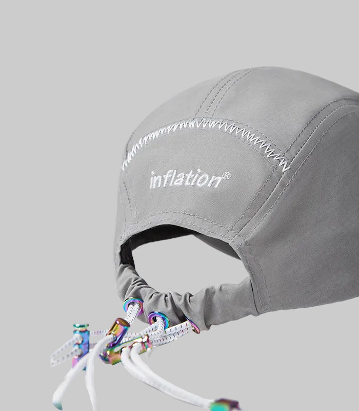 Light gray cap close-up with 'inflation' stitching and multicolor lanyard ends