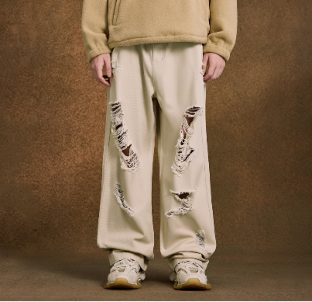 Ecru wide-leg jeans on model, distressed at knees and thighs with frayed edges