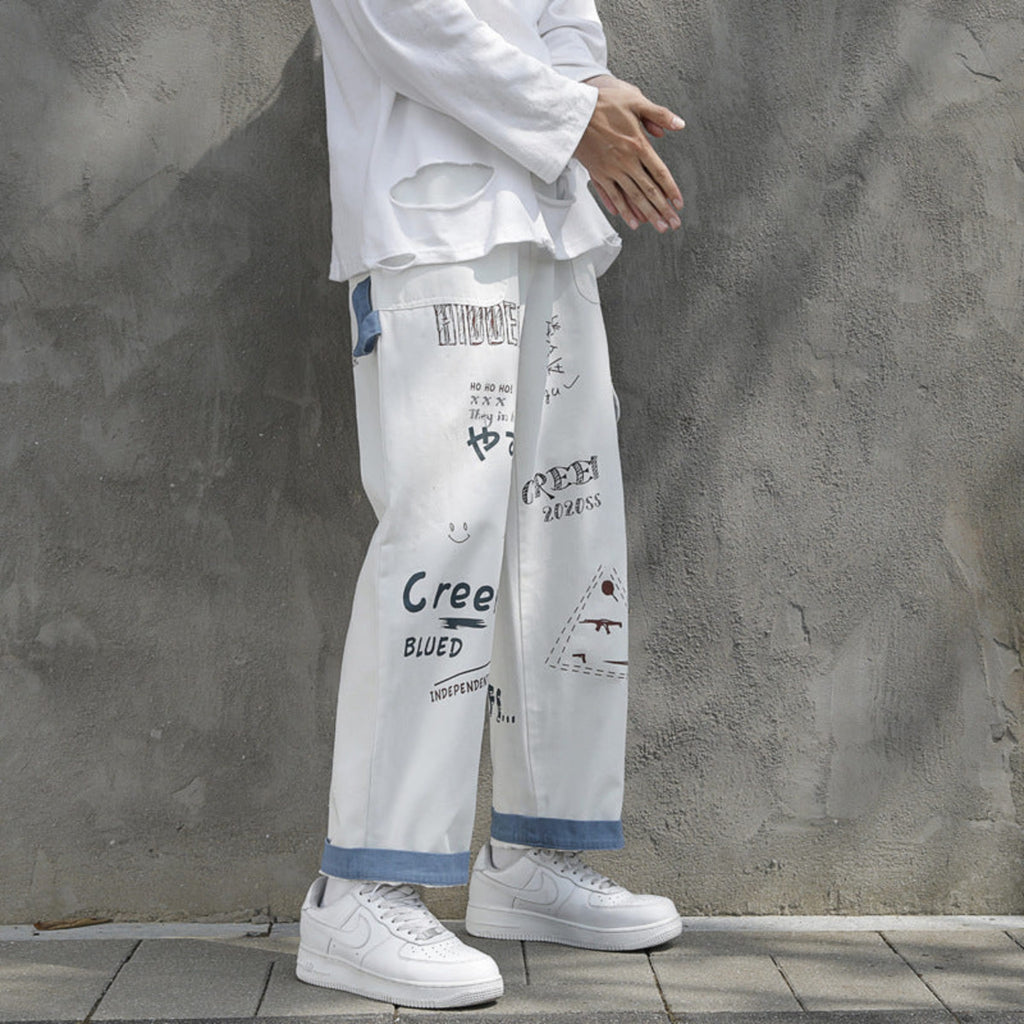 Ivory graffiti washed jeans with distressed blue paneling and assorted graphic print details