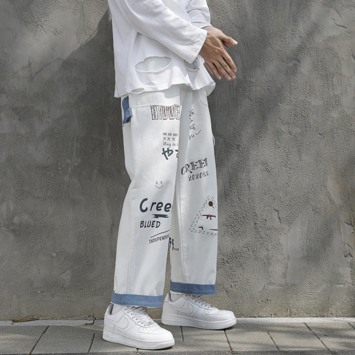 Ivory graffiti washed jeans with distressed blue paneling and assorted graphic print details