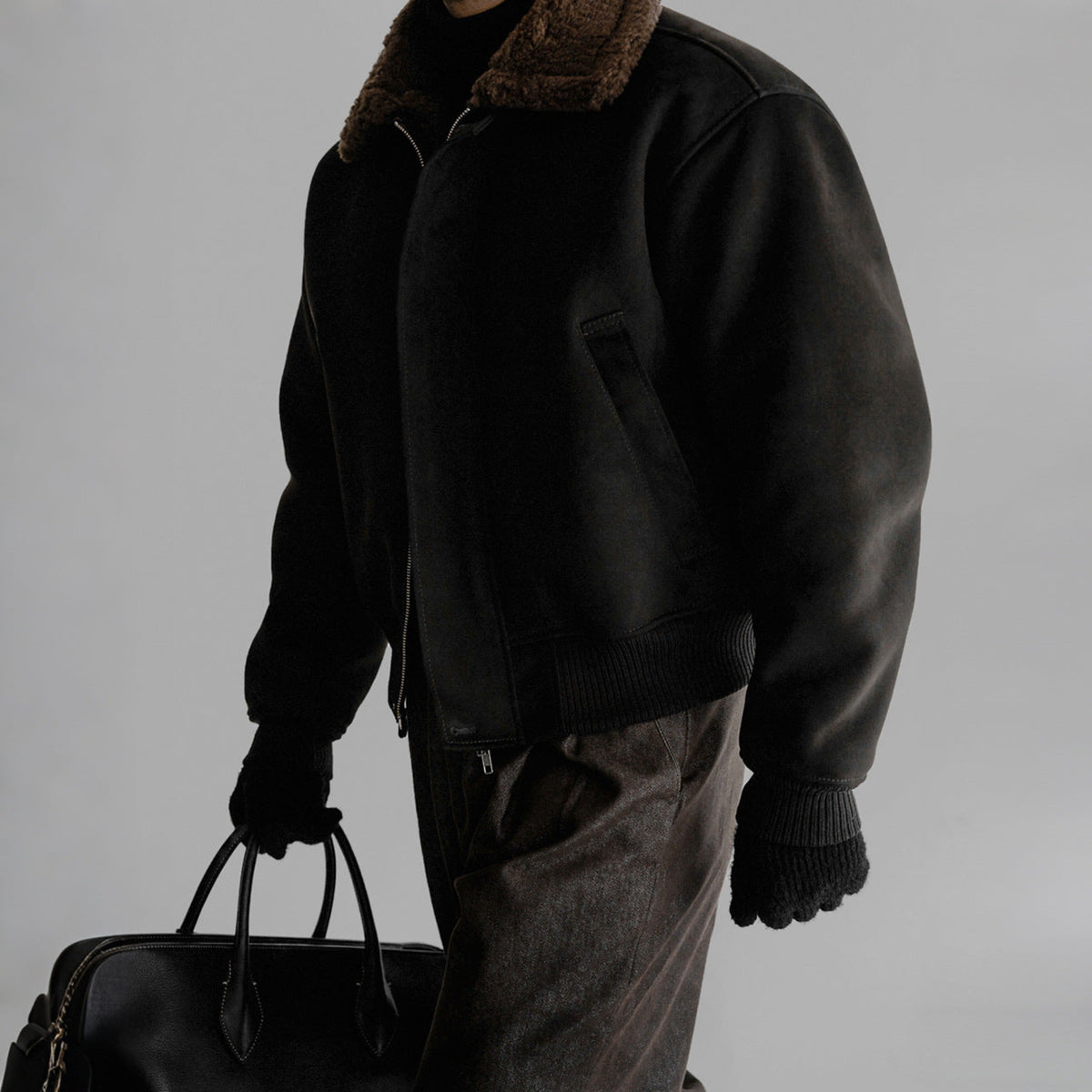 Black flight jacket side view with zip front, ribbed cuffs, and hand pockets