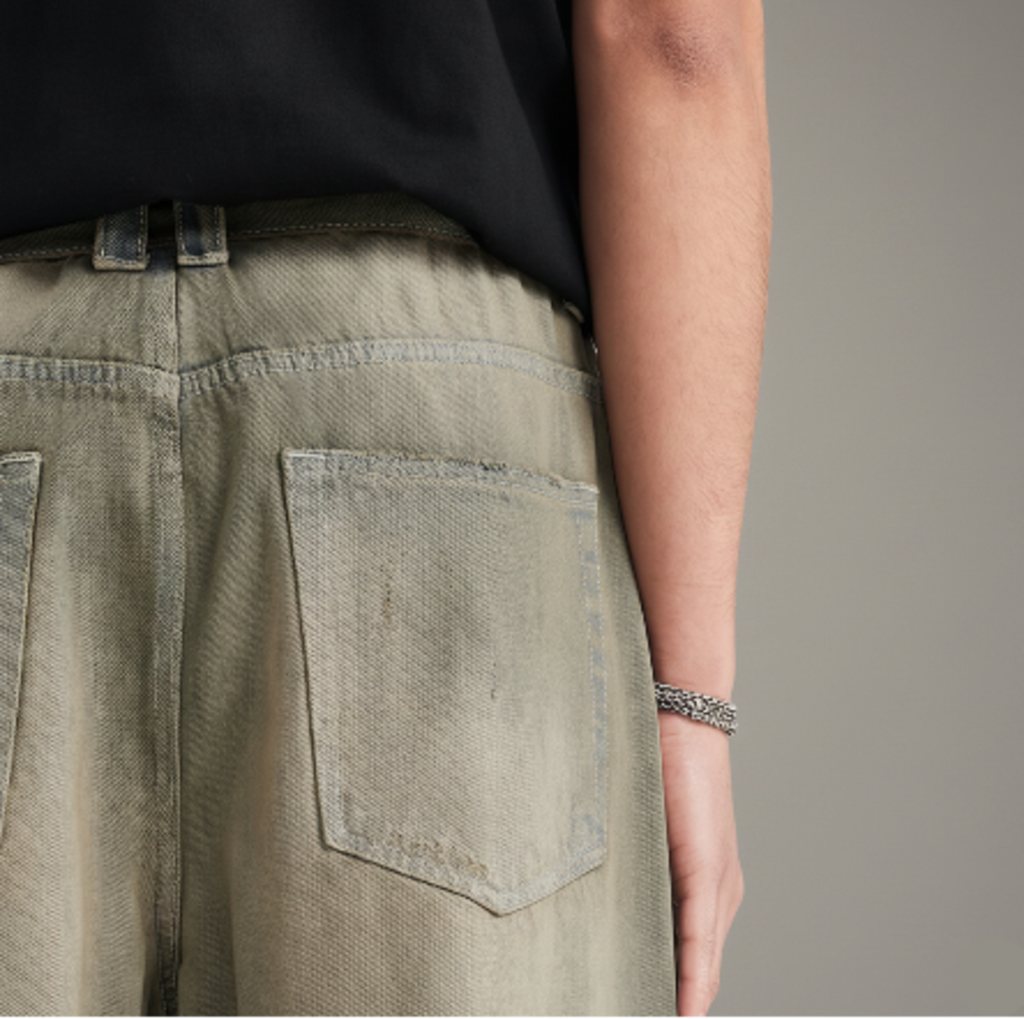 Washed ochre denim jeans detail: front yoke seam and flap pocket